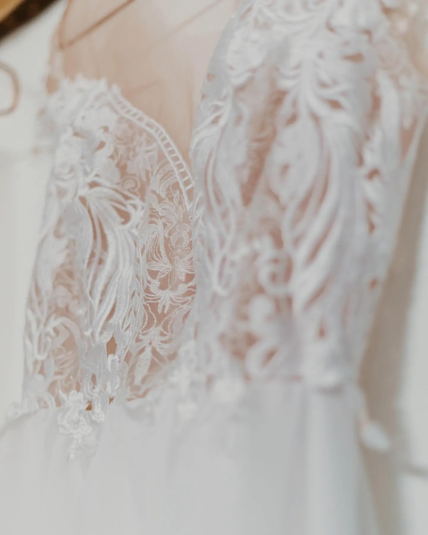 Cailyn’s custom wedding dress hanging with close-up lace bodice detail